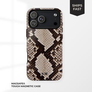 Peut inclure: Coque de téléphone à motif peau de serpent marron et beige. Le boîtier comporte un module caméra noir avec trois objectifs. Le texte "SHIPS FAST" est sur une bannière noire. L'étui est étiqueté "MAGSAFE® TOUGH MAGNETIC CASE".