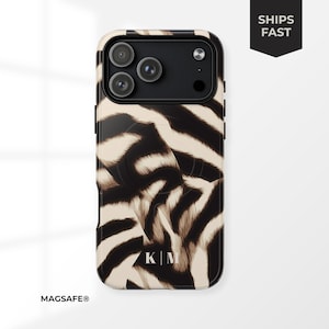 May include: A black and tan zebra print phone case with a black camera module. The case has the initials "K|M" at the bottom. The words "SHIPS FAST" are in a black banner. The word "MAGSAFE®" is at the bottom.