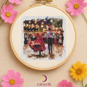 Puede incluir: Bordado de punto de cruz en un aro de madera que representa a una pareja bailando en un salón de baile. Los bailarines visten un vestido rojo y una camisa blanca. El aro está rodeado de flores de cosmos rosas y amarillas.