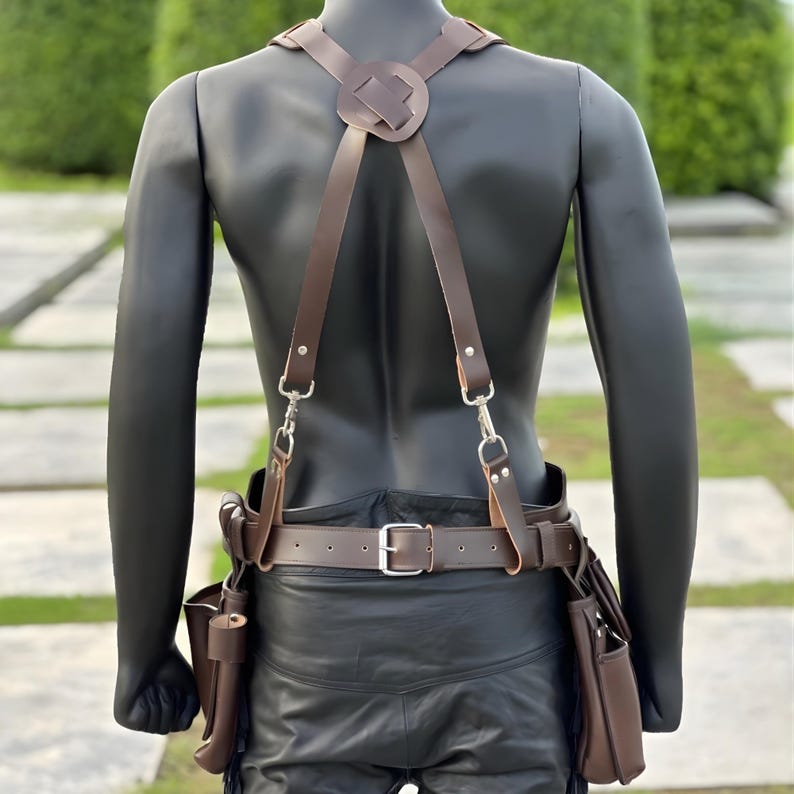 Back view of handmade leather tool belt showing adjustable cross suspenders, belt buckle, and detailed stitching for construction professionals.