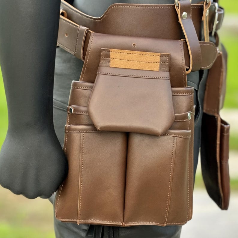 Detailed view of left leather tool pouch showing multiple pockets for nails, screws, and small tools.
