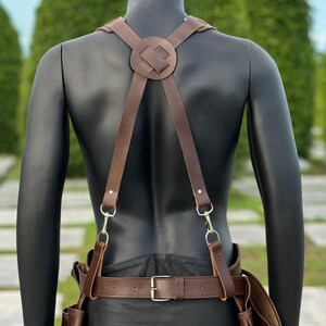 Detailed back view of suspenders’ cross-strap leather join and adjustable metal hooks for support.