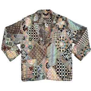 Puede incluir: Blazer patchwork multicolor con una mezcla de patrones geométricos y florales. La chaqueta presenta un cuello y dos bolsillos delanteros. Los colores incluyen marrón, verde y azul.
