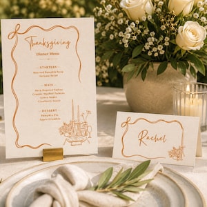 May include: A vertical Thanksgiving dinner menu card and a matching horizontal place card with the name Rachel, both featuring off-white paper, copper-colored line art borders, and elegant cursive text detailing starters, main courses, and desserts.