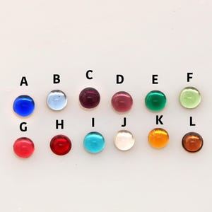 Pu&ograve; includere: Dodici perline di vetro rotonde in vari colori, tra cui blu, rosso, verde e trasparente. Le perline sono disposte in due file di sei, etichettate con le lettere da A a L.
