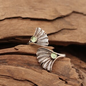 Puede incluir: Dos anillos de plata con un dise&ntilde;o de hoja de ginkgo y una piedra preciosa verde claro en el centro de cada hoja.