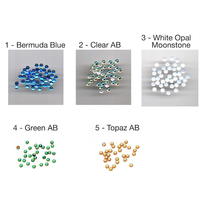 Pu&ograve; includere: Assortimento di piccole perline di vetro rotonde e iridescenti in vari colori, tra cui blu, verde, oro e bianco. Le perline sono disposte in gruppi di cinque, con ogni gruppo etichettato con un numero e un nome di colore. 1 - Blu delle Bermuda, 2 - Chiaro AB, 3 - Pietra lunare opale bianca, 4 - Verde AB, 5 - Topazio AB.
