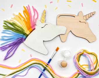 May include: A DIY unicorn craft kit featuring a white painted unicorn head with a rainbow yarn mane, a wooden unicorn head, paint, and a paintbrush. The kit includes colorful yarn in shades of pink, orange, yellow, green, blue, and purple.