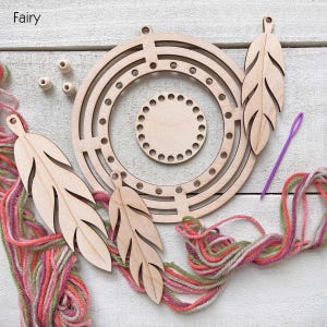 May include: A wooden dream catcher kit with a circular frame, feather cutouts, wooden beads, and colorful yarn. A purple needle is also included. The word "Fairy" is in the top left corner.