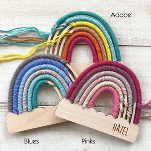Pu&ograve; includere: Tre decorazioni da parete a forma di arcobaleno fatte a mano nei colori Blues, Pinks e Adobe. Ogni arcobaleno presenta una base in legno a forma di nuvola e un nome inciso. Gli arcobaleni sono realizzati con filato colorato.
