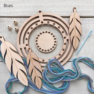 May include: A craft kit with wooden components for a dream catcher. The kit includes a circular frame, feather-shaped cutouts, wooden beads, and blue and gray yarn. A light blue needle is also included. The word "Blues" is in the upper left corner.
