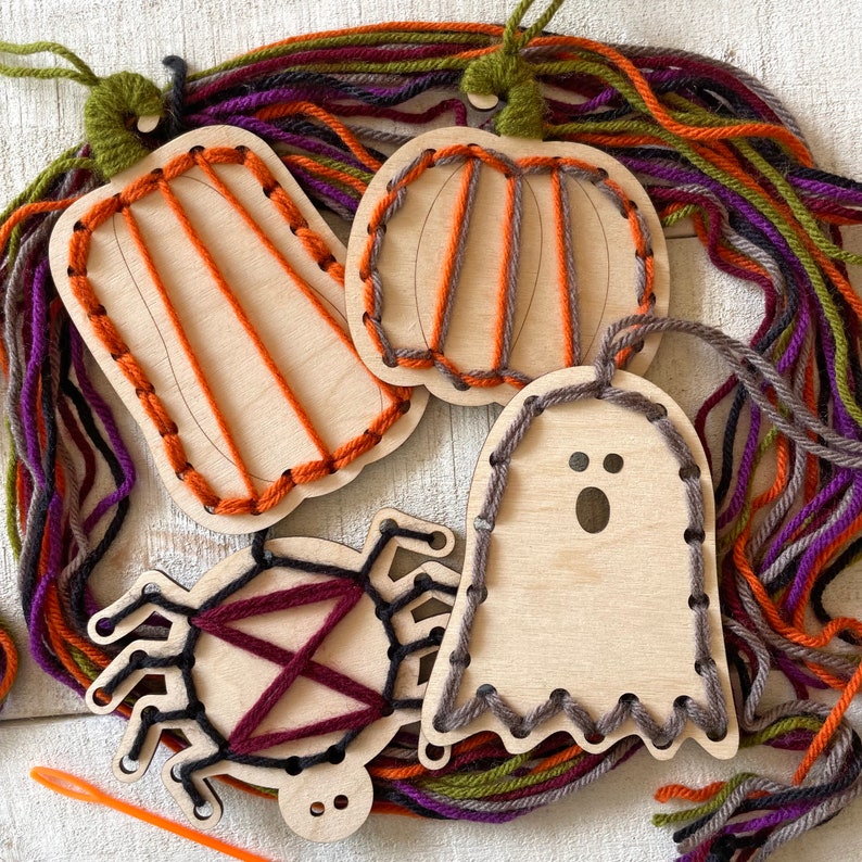 以下が含まれることがあります： カボチャ、幽霊、クモなど、ハロウィーンをテーマにした木製ひも通しおもちゃ。各おもちゃは明るい色の木でできており、ひも通し用のカラフルな糸が付いています。おもちゃは、オレンジ、紫、緑、グレーの色合いのカラフルな糸で囲まれています。