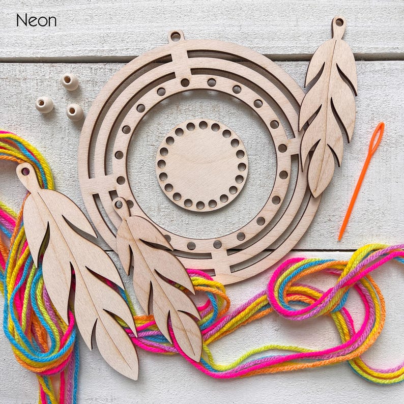 May include: A wooden dream catcher kit with a circular frame, feather cutouts, wooden beads, and colorful yarn. An orange needle is also included. The word "Neon" is in the upper left corner.
