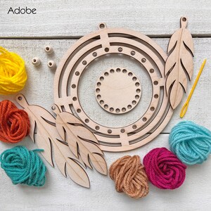 May include: A wooden dream catcher kit with a circular frame, feather cutouts, and colorful yarn in yellow, orange, teal, pink, and brown. Includes wooden beads and a yellow needle. The kit is designed for crafting.