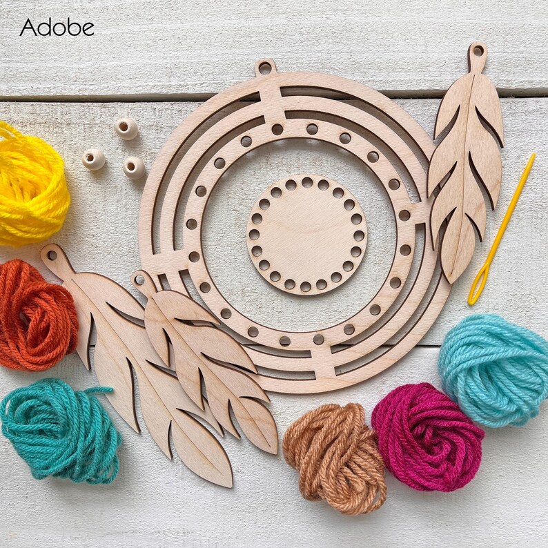 May include: A wooden dream catcher kit with a circular frame, feather cutouts, and colorful yarn in yellow, orange, teal, pink, and brown. Includes wooden beads and a yellow needle. The kit is designed for crafting.