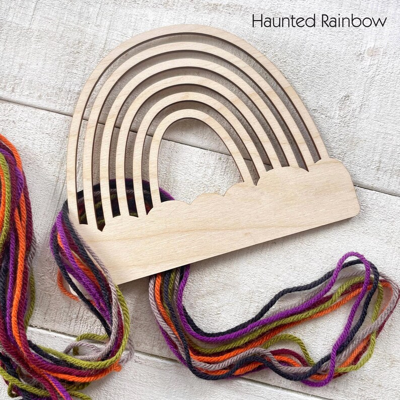 Pu&ograve; includere: Un telaio per tessitura a forma di arcobaleno in legno con base a nuvola. Il telaio &egrave; realizzato in legno chiaro e presenta pi&ugrave; fessure arcuate. Filato colorato nelle tonalit&agrave; dell'arancione, viola, verde e grigio &egrave; attaccato al telaio. Il testo "Haunted Rainbow" &egrave; visibile.