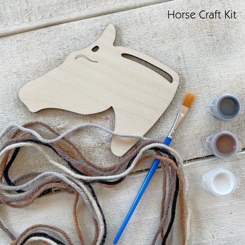 Puede incluir: Un kit de manualidades de cabeza de caballo de madera con el texto "Horse Craft Kit". El kit incluye un recorte de cabeza de caballo de madera, pintura, un pincel e hilo de varios colores. Los colores de la pintura son gris, marr&oacute;n y blanco.