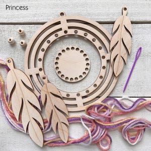 May include: A wooden dream catcher kit with a circular frame, feather-shaped cutouts, and a small circular base. The kit includes wooden beads, a purple needle, and colorful yarn in shades of pink, purple, and yellow. The word "Princess" is in the top left corner.