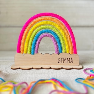 Pu&ograve; includere: Decorazione arcobaleno colorata con base in legno. L'arcobaleno presenta tonalit&agrave; vibranti di rosa, giallo, verde, blu e viola. La base in legno ha un bordo smerlato e il nome "GEMMA" &egrave; inciso.