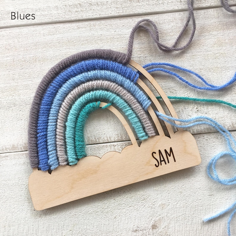 Pu&ograve; includere: Un'applique a forma di arcobaleno in legno con filato blu, grigio e verde acqua. La parola "Blues" &egrave; in alto a sinistra. Il nome "SAM" &egrave; inciso sulla base di nuvola in legno. Fili di filo si estendono dalla parte superiore.