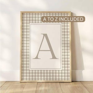 May include: A framed print featuring the letter "A" in a neutral color, centered on a white background. The frame has a light wood finish, and the border is a tan and white gingham pattern. The text "A TO Z INCLUDED" is in a banner at the top.
