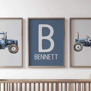 May include: Three framed prints featuring a blue tractor illustration and a personalized initial and name. The central print displays a large white letter "B" and the name "BENNETT" on a blue background. The other two prints show a blue tractor.