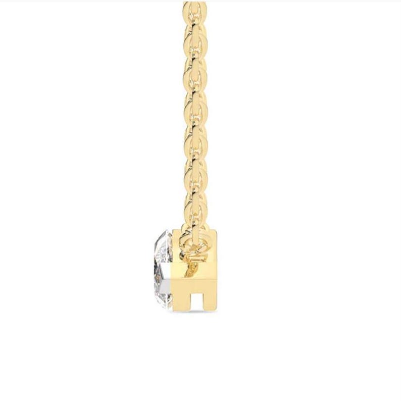 May include: A delicate gold necklace featuring a single, clear diamond pendant. The diamond is set in a square gold setting and hangs from a fine, linked gold chain. The necklace is displayed against a white background.