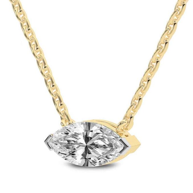 May include: A gold necklace featuring a marquise-cut diamond pendant. The diamond is set in a gold bezel and hangs from a delicate gold chain. The chain has a textured, link design. The necklace is displayed against a white background.