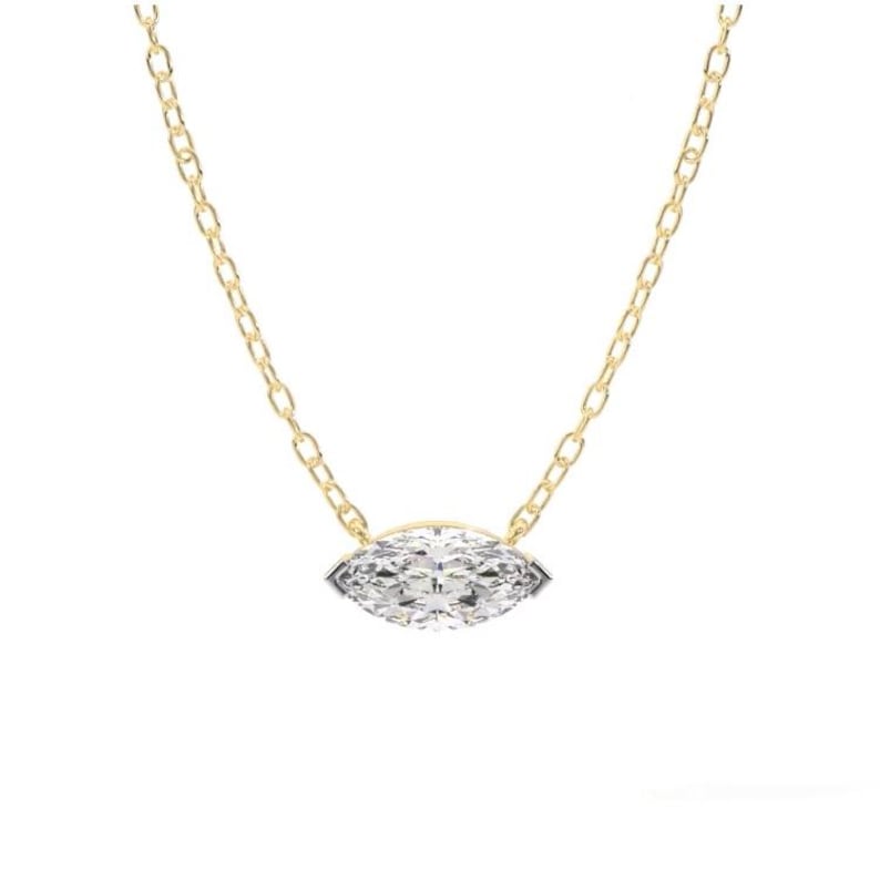 May include: A gold chain necklace featuring a marquise-cut diamond pendant. The diamond is set in a bezel setting and sparkles with many facets. The chain is delicate and has a classic link design.