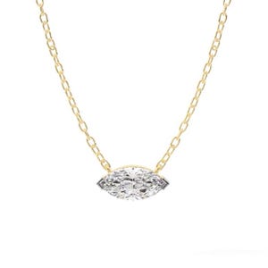May include: A delicate gold chain necklace featuring a marquise-cut diamond pendant. The diamond is set in a bezel setting and sparkles with numerous facets. The chain is a classic link style, creating a timeless piece of jewelry.