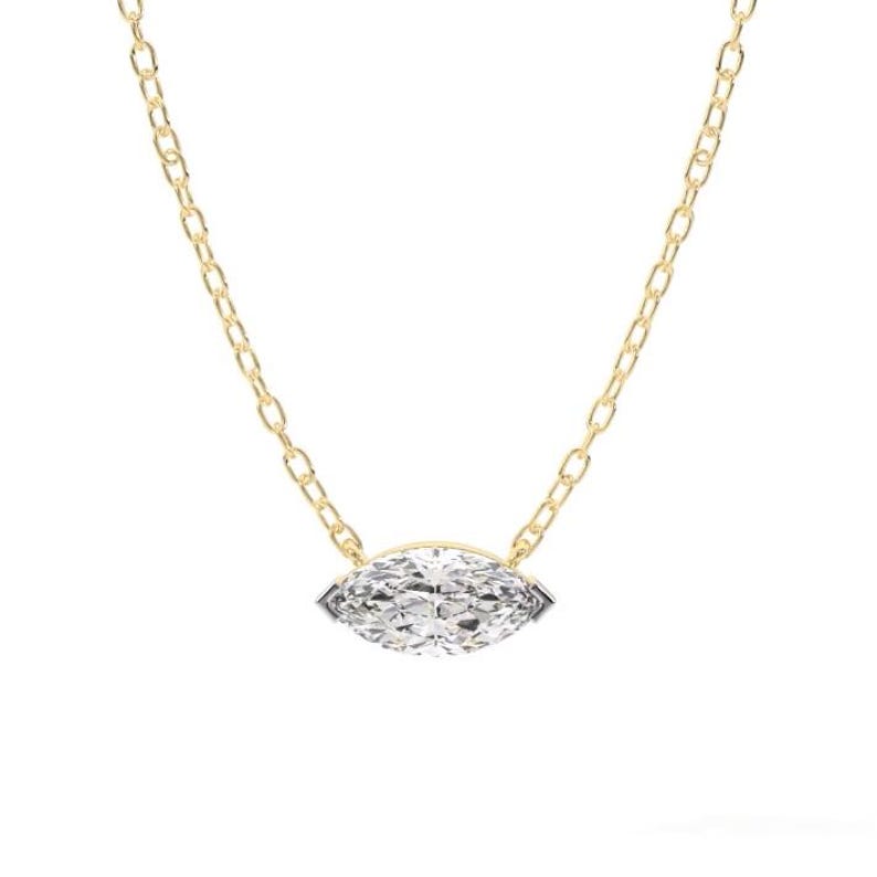 May include: A delicate gold chain necklace featuring a marquise-cut diamond pendant. The diamond is set in a bezel setting and sparkles with numerous facets. The chain is a classic link style, creating a timeless piece of jewelry.