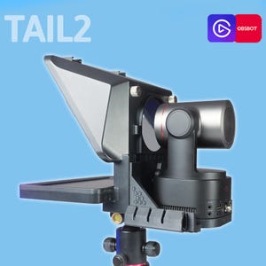 May include: A black OBSBOT Tail2 camera mounted on a tripod, featuring a cylindrical lens housing with a red accent ring, a large rectangular lens hood, and a side-mounted screen. The text TAIL2 is visible in the upper left corner of the frame.