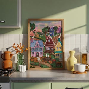 以下が含まれることがあります： 額縁に入った絵画は、カラフルな家、カボチャ、そして「Pumpkin Patch」のテキストが描かれた気まぐれな秋のシーンを描いています。 このアートワークは、ピンク、青、赤、黄色など、さまざまな色を特徴とし、魅力的で季節感のある美学を生み出しています。