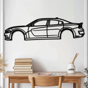 Puede incluir: Arte de pared de metal negro de una silueta de coche. El coche es un sedán moderno con un diseño elegante. El arte está montado en una pared blanca.