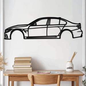 Könnte beinhalten: Schwarze Metallumriss einer Limousine, Seitenansicht, an einer weißen Wand montiert. Das Auto hat ein elegantes Design.
