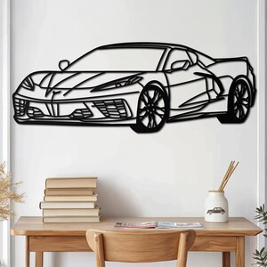 Könnte beinhalten: Schwarz-weiße Linienkunst-Wanddekoration eines Sportwagens. Das Auto ist zur linken Seite des Bildes gerichtet. Das Auto hat ein elegantes Design mit einer langen Motorhaube und einem niedrigen Profil.
