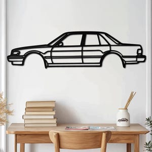 May include: Black metal wall art depicting a vintage car silhouette. The car is a saloon with a long bonnet and a rounded roof. The art is mounted on a white wall.