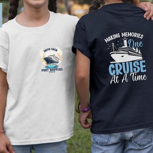 Op de afbeelding: Twee kinderen dragen bijpassende t-shirts. Eén is wit met een cruiseschip-afbeelding en de tekst "Smith Crew Port Hoppers 2025". De andere is marineblauw met een cruiseschip-afbeelding en de tekst "Making Memories One Cruise At A Time."