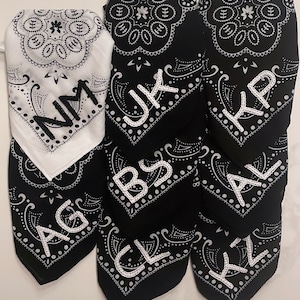 May include: Seven black bandana style fabric squares with white paisley designs and white embroidered letters. The letters spell out "AG, BS, CL, JK, KP, AL, KZ".