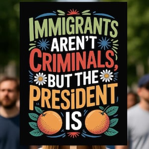 May include: A black sign with the text "IMMIGRANTS AREN'T CRIMINALS, BUT THE PRESIDENT IS" in various colors. The sign features orange illustrations of oranges and is held by a person in a crowd.