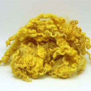 May include: A pile of bright yellow curly wool fibers.