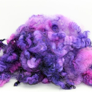 May include: A pile of purple, pink, and blue wool roving. The wool is soft and fluffy, and it is perfect for spinning or felting.