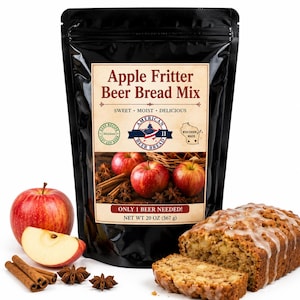 May include: A black stand-up pouch of Apple Fritter Beer Bread Mix with a label featuring red apples, cinnamon sticks, and star anise. The text reads Apple Fritter Beer Bread Mix, Sweet, Moist, Delicious, Only 1 Beer Needed, and Net Wt 20 oz (567 g).