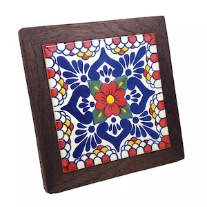 May include: A square ceramic tile with a colorful floral design in shades of red, blue, yellow, and green. The tile is framed in a dark wood frame.