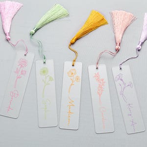 Op de afbeelding: Zes transparante acryl bladwijzers met kleurrijke kwastjes. Elke bladwijzer heeft een bloemenontwerp en een naam in bijpassende kleur: Brenda, Sophia, Madison, Caroline en Kerry Ann. De kwastjes zijn roze, groen, geel, perzik en paars.