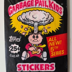 May include: A black Garbage Pail Kids sticker pack featuring a cartoon character with an explosion above its head. The pack includes the text "ALL NEW! 5TH SERIES" and "5 STICKERS 1 STICK BUBBLE GUM."