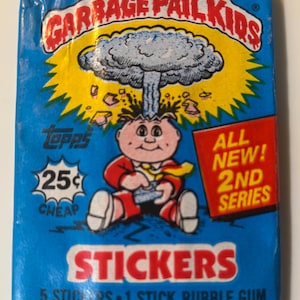 May include: A blue Garbage Pail Kids sticker pack featuring a cartoon character with a mushroom cloud explosion from their head. The pack includes the text "25¢ CHEAP", "ALL NEW! 2ND SERIES", and "STICKERS".