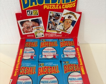 May include: A vintage baseball card and puzzle box set. The box is red with the word "BASEBALL" in large blue and yellow letters. The set includes baseball cards and puzzles featuring baseball players. The price is 30¢.