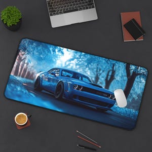 May include: A blue Dodge Challenger muscle car driving through a forest with a blue and white color scheme. The car is in focus and the background is blurred.