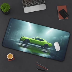 May include: A green Dodge Challenger muscle car in a dimly lit garage setting. The car is a modern model with a sleek design and large wheels. The background is a dark gray with some light coming from the ceiling.